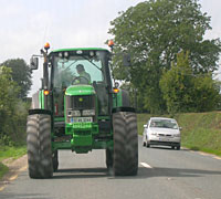 Farmer driving his tractor in reverse down the road